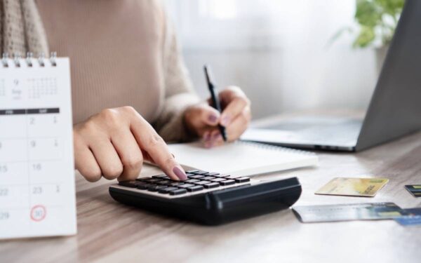 Pessoa usando calculadora e anotações.
