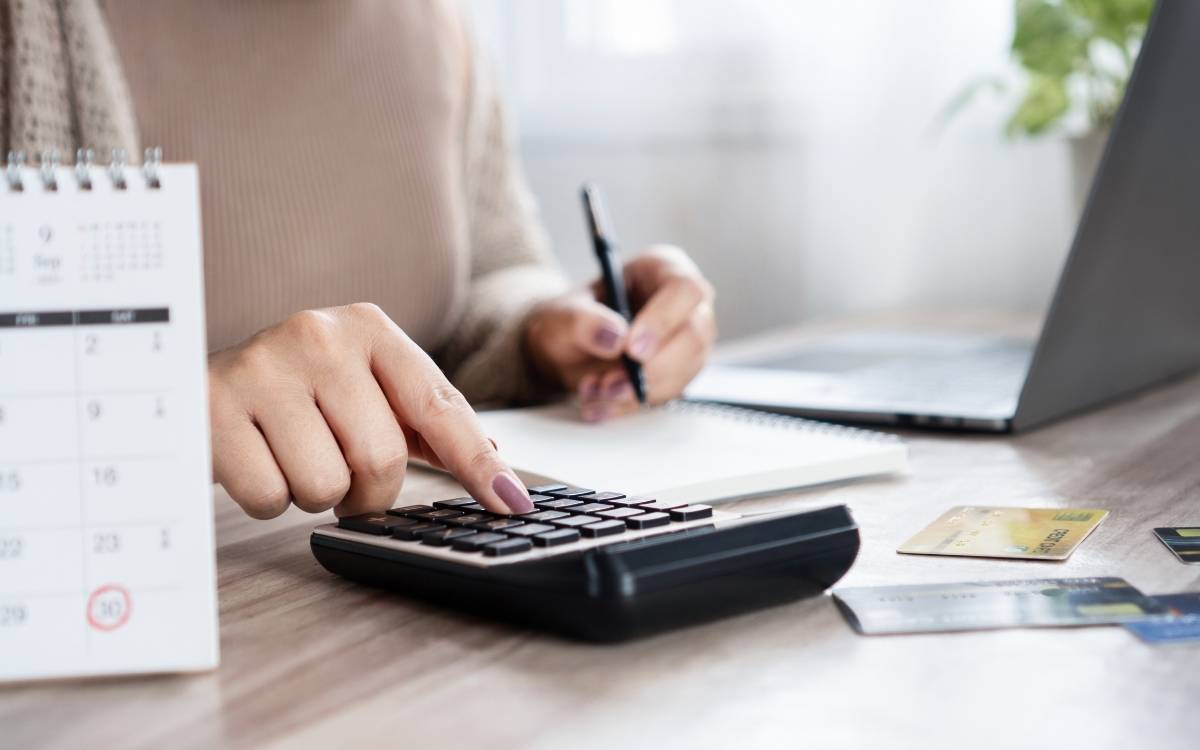 Pessoa usando calculadora e anotações.